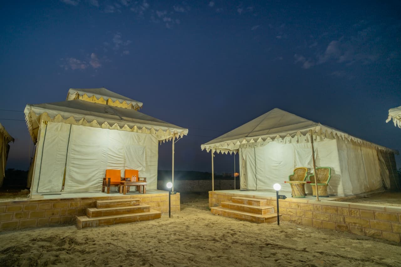 Two Deluxe Swiss tents with sandstone steps under a twilight desert sky