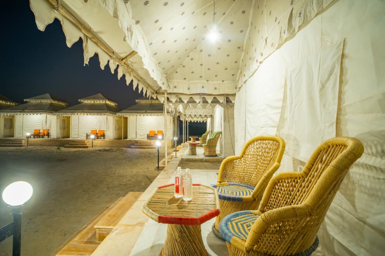 Deluxe Swiss tent veranda with woven cane table and chairs looking onto the camp