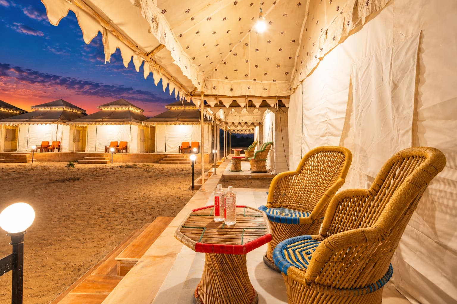 Deluxe Swiss tent veranda with woven cane table and chairs looking onto the camp