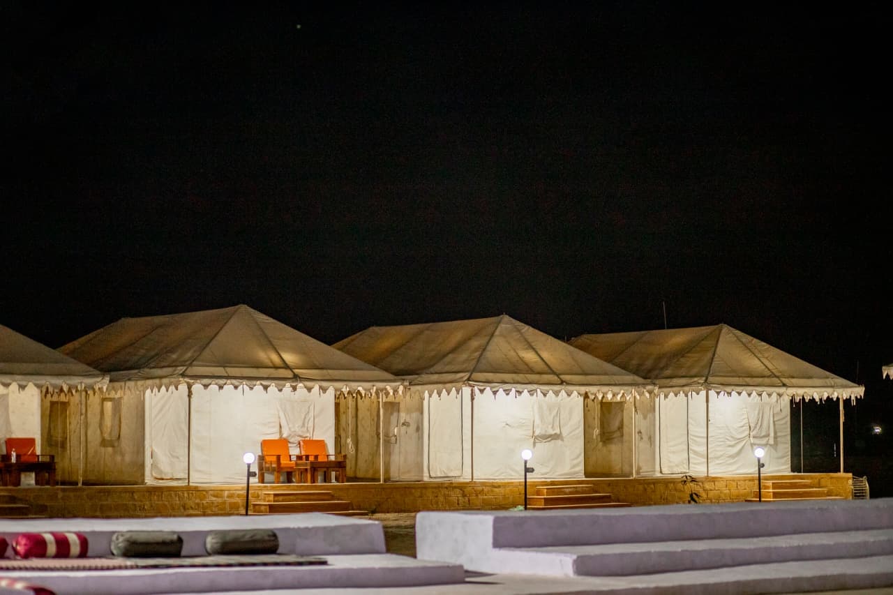 Open-air cultural programme seating with tents lit up behind at night