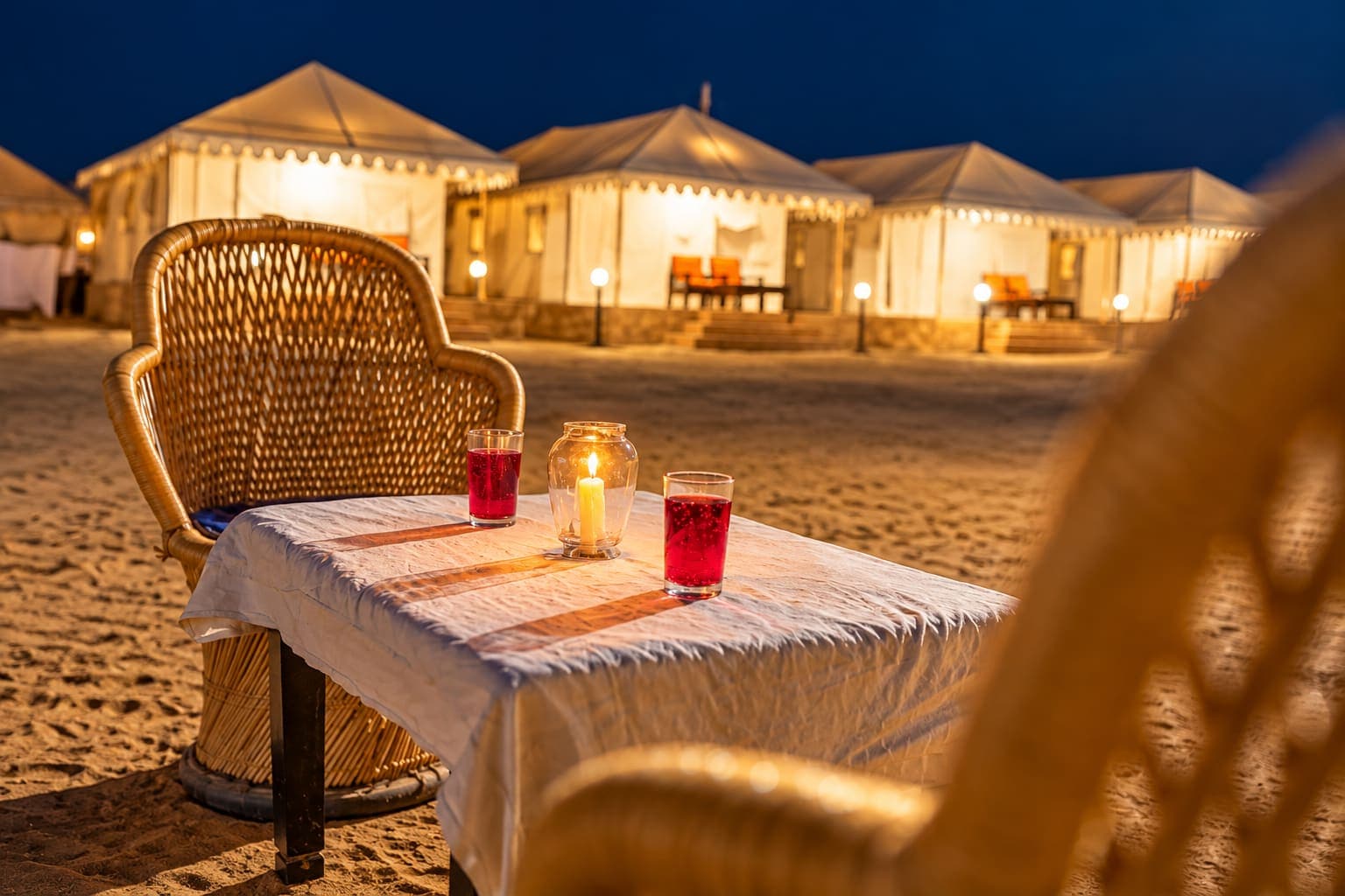 Welcome drinks and a candle lantern on a dining table set outdoors on the dunes