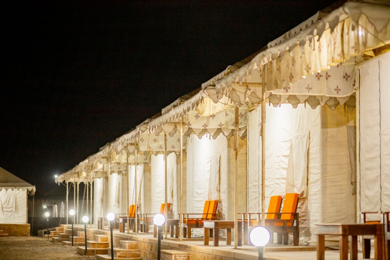 Row of illuminated luxury Swiss tents with private verandas at Desert Overnight Camp, Sam Sand Dunes Jaisalmer