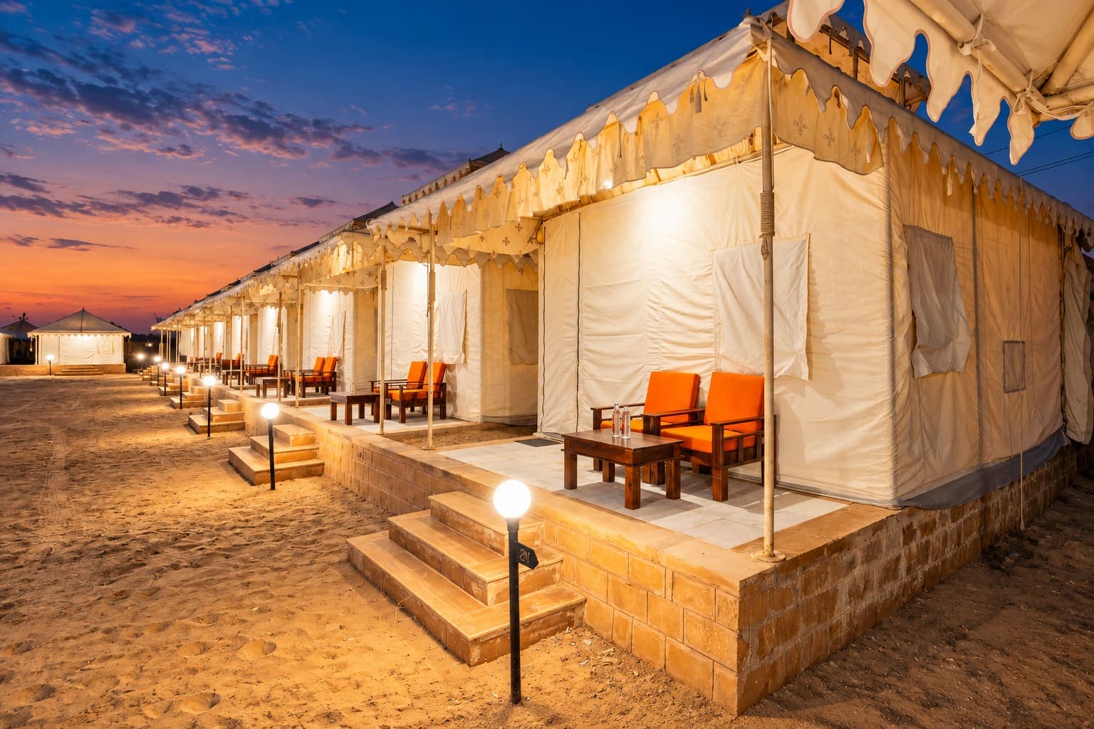 Royal Maharaja Swiss tent verandas with orange lounge seating at twilight