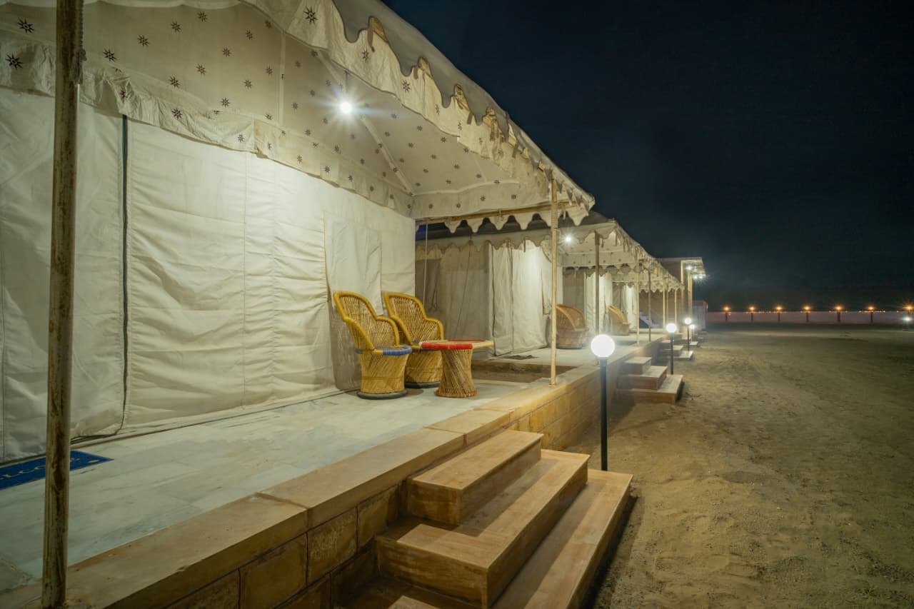 Swiss tent veranda with cane chairs and a lantern-lit walkway at night