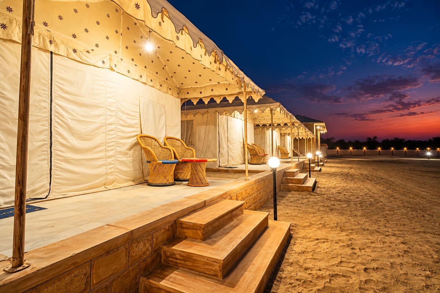 Swiss tent veranda with cane chairs and a lantern-lit walkway at night